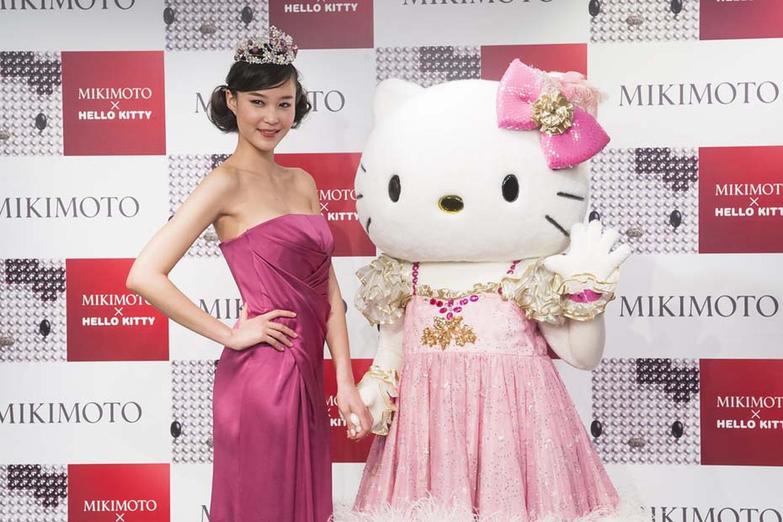 Hello Kitty strikes a pose with a model wearing the Hello Kitty tiara at the Mikimoto x Hello Kitty launch event at Mikimoto's flagship boutique in Tokyo