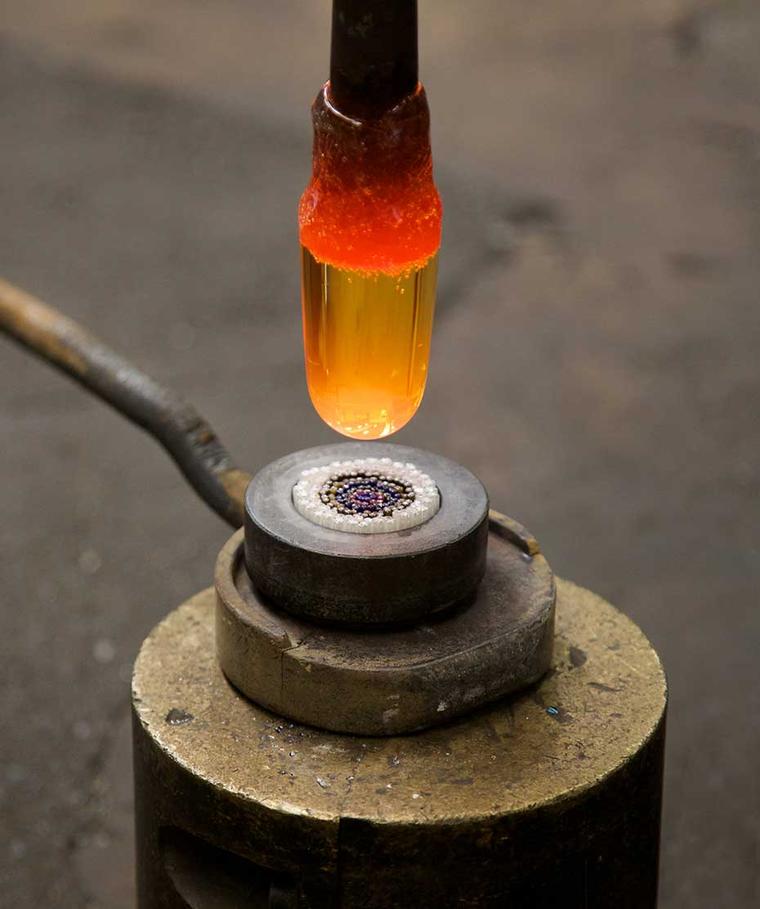 Lined up like sticks of barley sugar or candy canes, the rods containing crystal and enamel are cut into 7mm portions and arranged vertically in a cast-iron bowl to form a carpet of flowers.