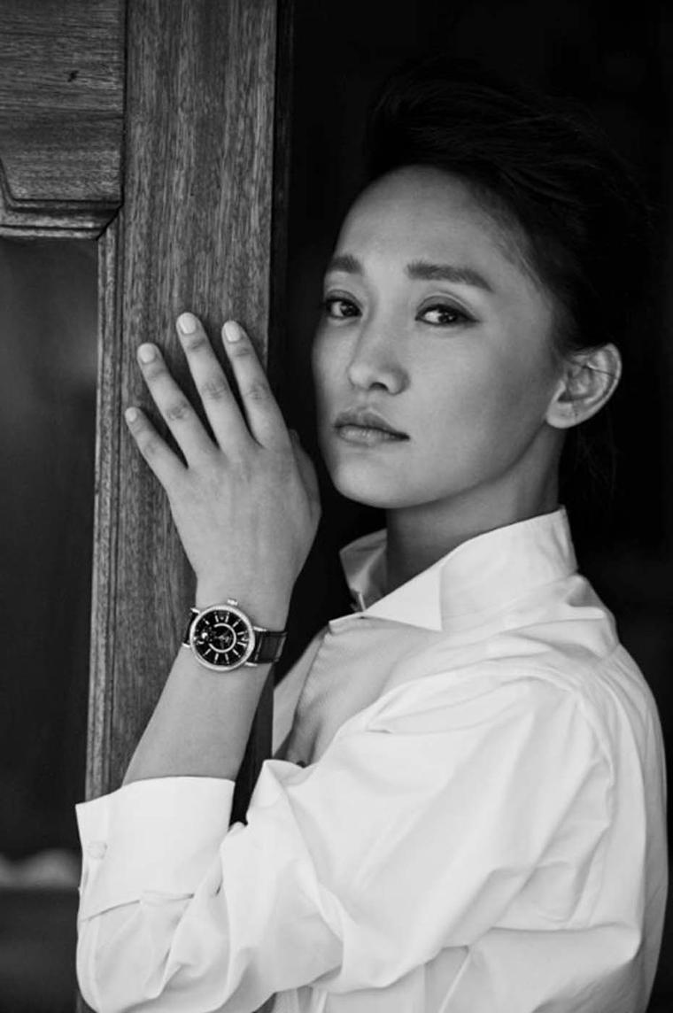 Zhou Xun wearing the IWC Portofino Midsize Automatic Moon Phase watch with a black mother-of-pearl dial and an alligator strap.