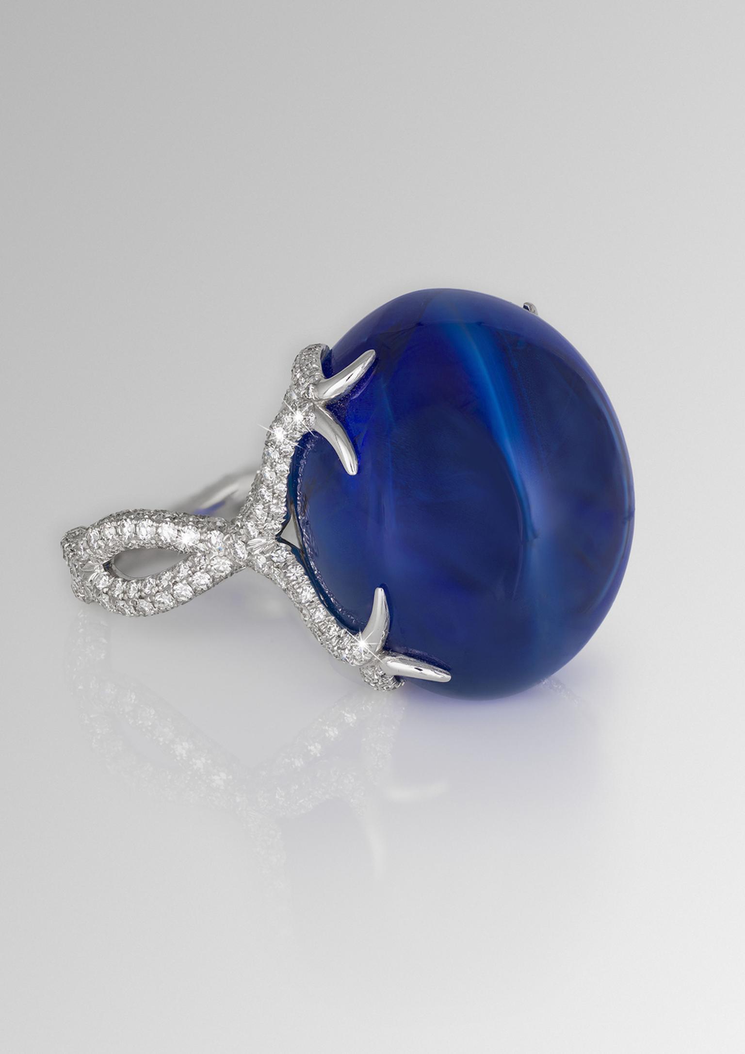 David Morris ring featuring a central 64.55ct blue Burmese double cabochon sapphire with a twisting diamond band.