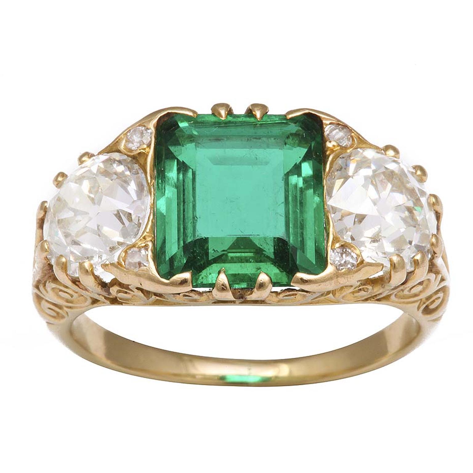 A La Vieille Russie Victorian engagement ring in gold with a central-set Colombian emerald flanked by old-mine diamonds.