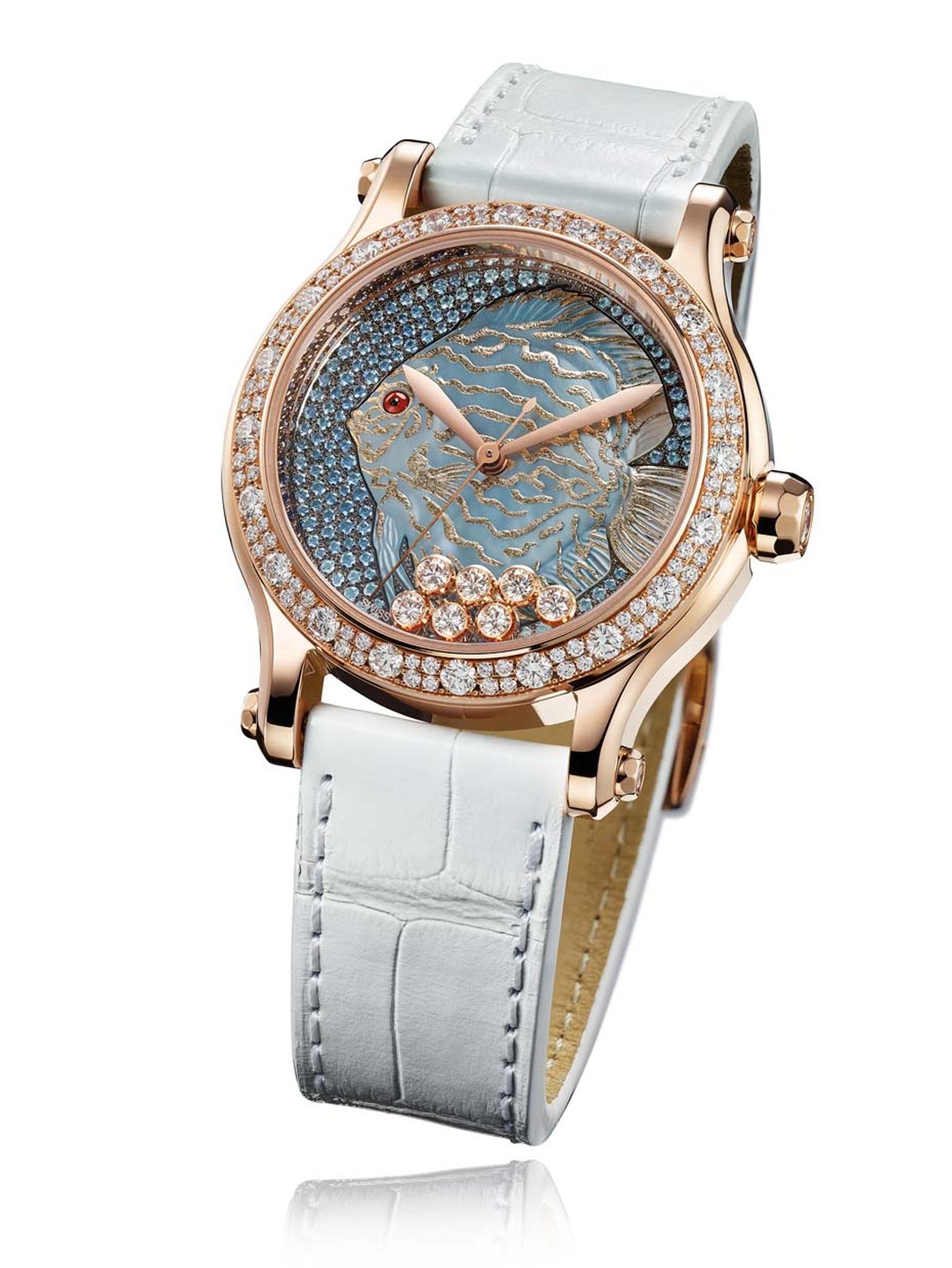 The new Chopard Happy Fish watch showcases the skill of the Maison's artisans, who have engraved the fish from shimmering mother-of-pearl and enhanced its contours with gold leaf. The graded shades of snow-set blue sapphires to simulate the sea are housed