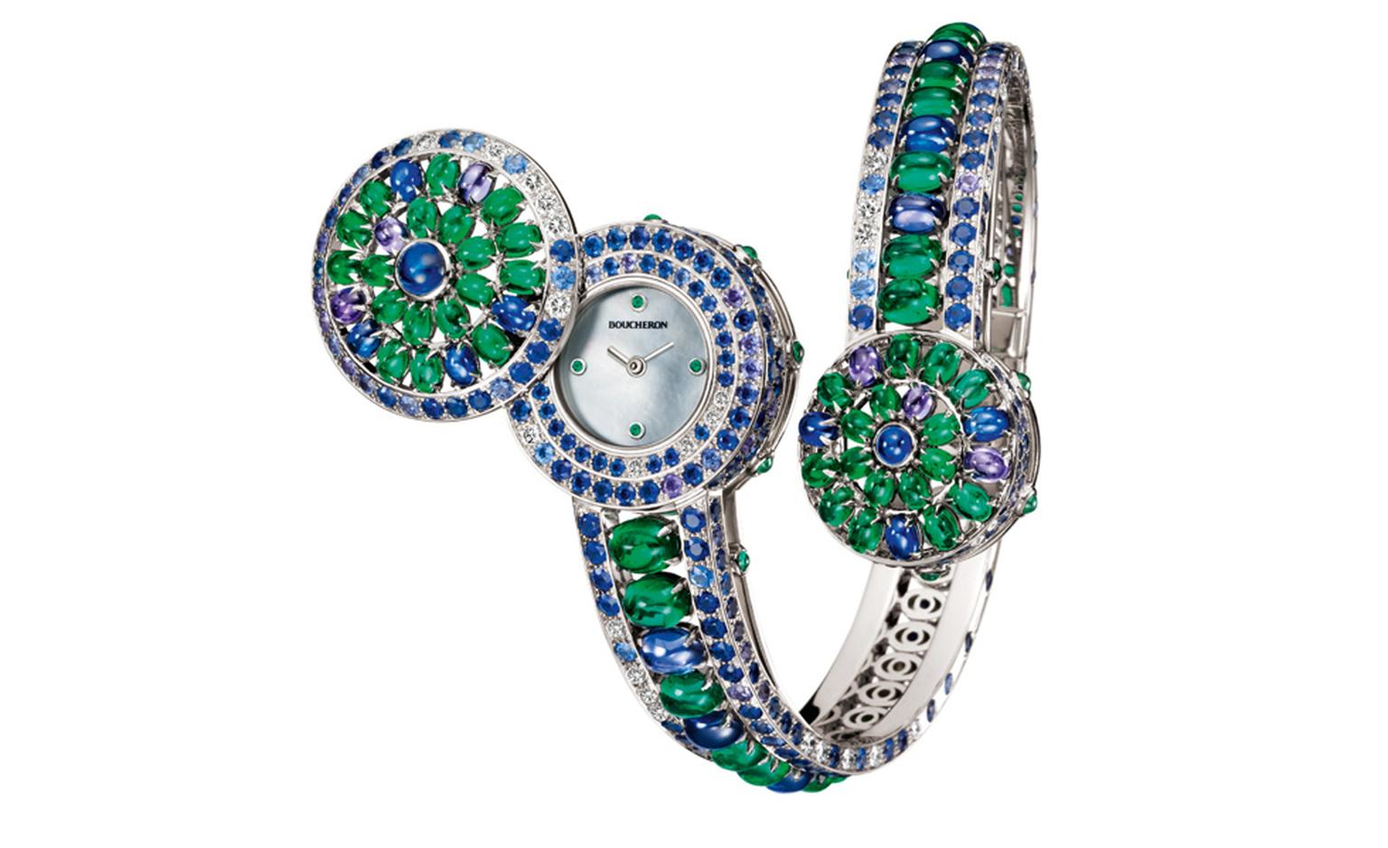 Boucheron Capriccioli watch bracelet paved with blue and purple round cabochon sapphires, oval cabochon emeralds,  blue and purple sapphires and diamonds, on white gold. A watch is hidden under the larger pattern of the bracelet. It opens by a s...