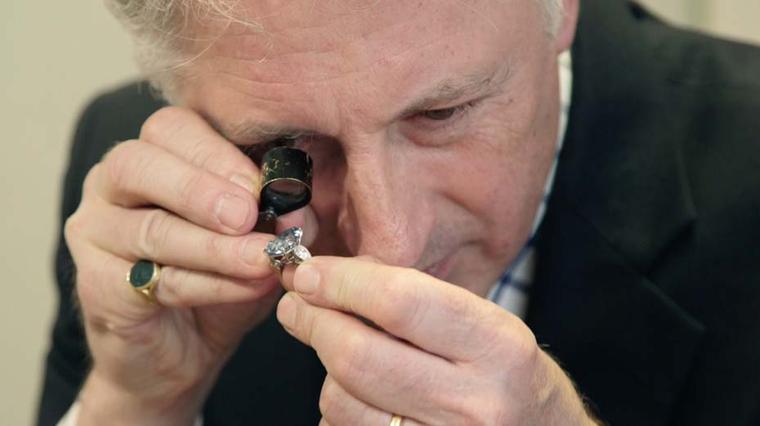 David Warren, Christie's International Director of Jewellery, examines the 13.22ct flawless Vivid blue diamond - the most vibrant and therefore most desirable of coloured diamonds - with a loupe