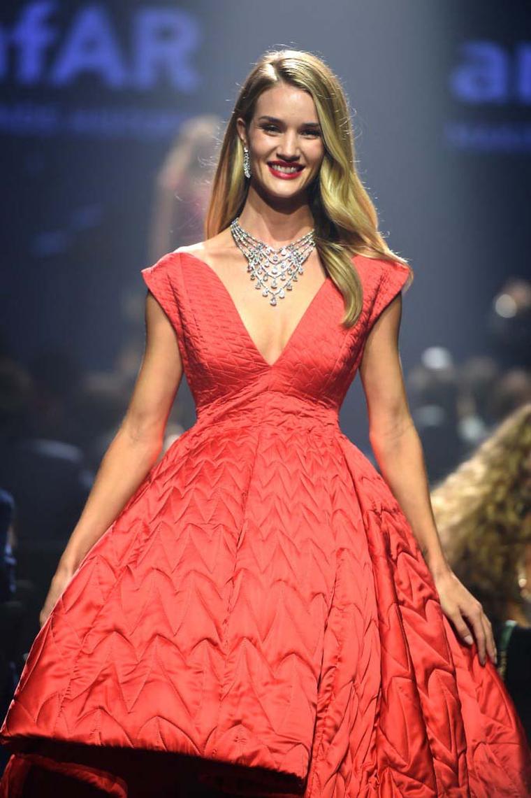 Rosie Huntington-Whiteley beams as she walks down the catwalk in Bulgari jewels. A red-themed fashion show curated by Carine Roitfeld formed part of the 2014 amfAR charity fundraiser in Cannes