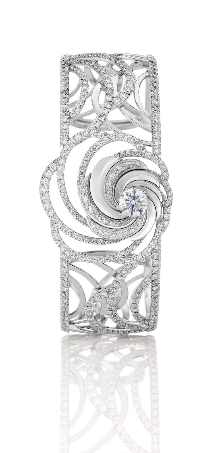 De Beers Aria diamond bracelet, with a series of swirling white gold ribbons set with pavé diamonds surrounding a central brilliant-cut diamond.