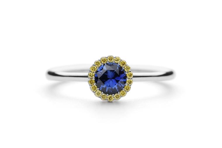 Andrew Geoghegan Cannelé engagement ring in white gold with a brilliant-cut blue sapphire encircled by yellow sapphires.