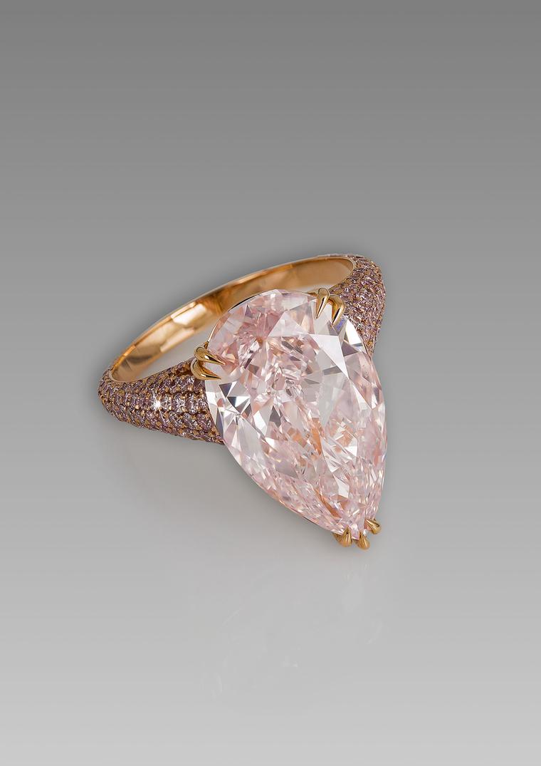 David Morris pear-shaped pink diamond ring set against a glimmering backdrop of pavé pink diamonds on a rose gold band.