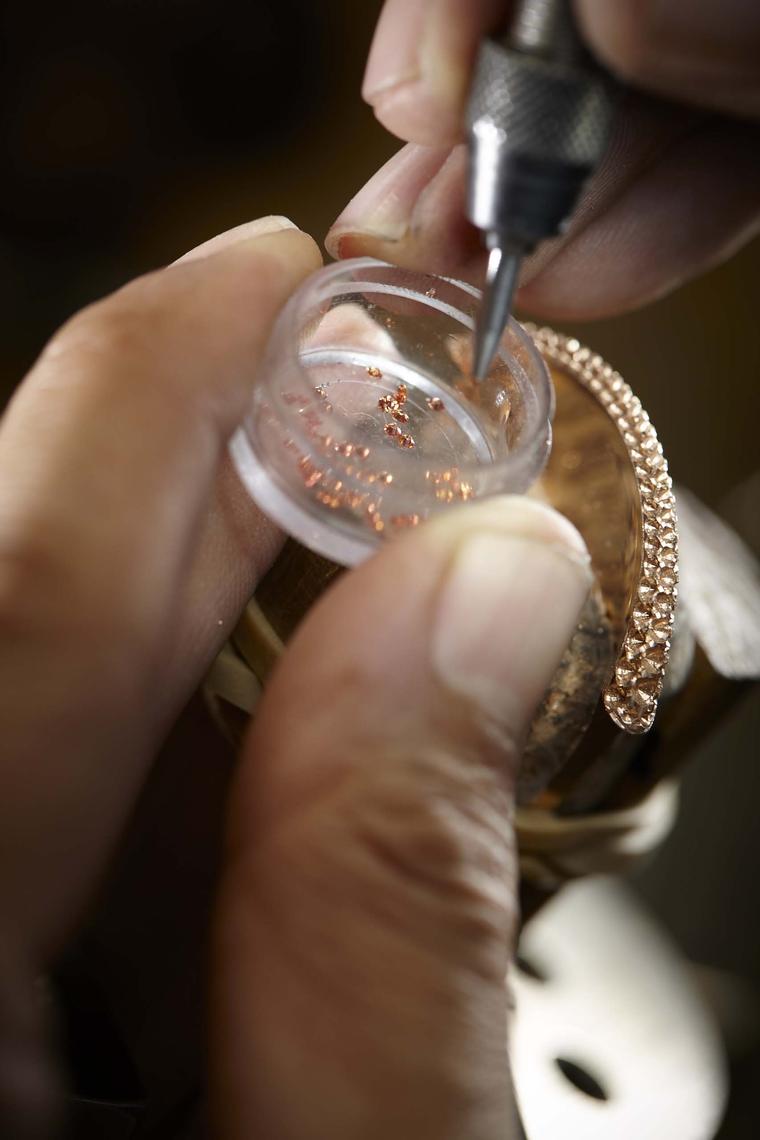 Tiny orange sapphires are set into the case by hand.