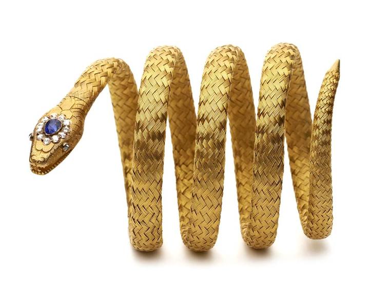 A Victorian sapphire and rose diamond gold coiled bracelet ending in a snake's head with an open mouth and two rose-cut diamond eyes and a rose-cut diamond and pear-shaped sapphire head. Exhibited by Hancocks.