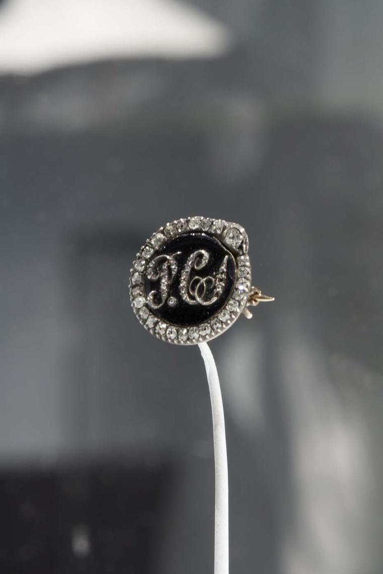 A gold Mourning brooch with the loved one's initials inscribed in diamonds set in onyx and surrounded by diamonds.