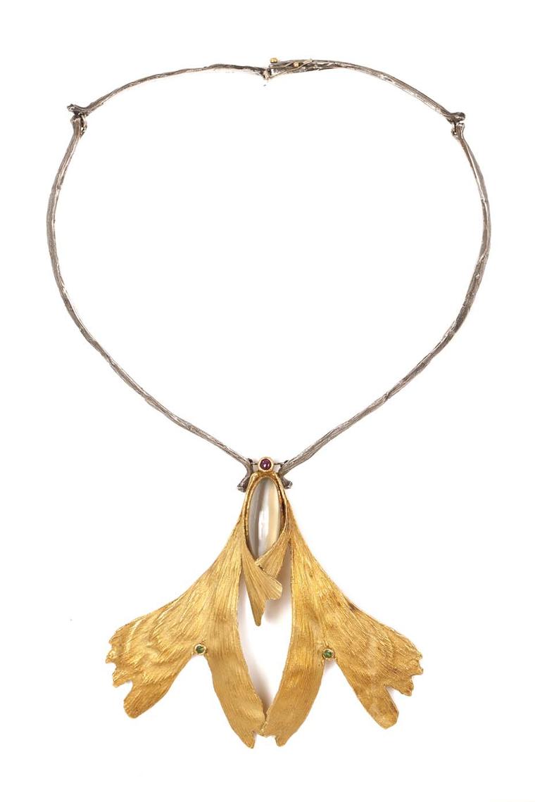Elizabeth Defner necklace featuring two gold chased ginko biloba leaves set with round mixed-cut emeralds, supporting a honey coloured moonstone and a round mixed-cut ruby