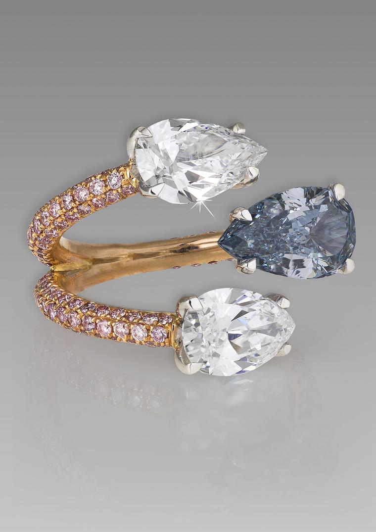 A unique David Morris blue diamond engagement ring featuring a rose gold and melée diamond band that separates to meet two pear-shaped white diamonds and one pear-shaped blue diamond.