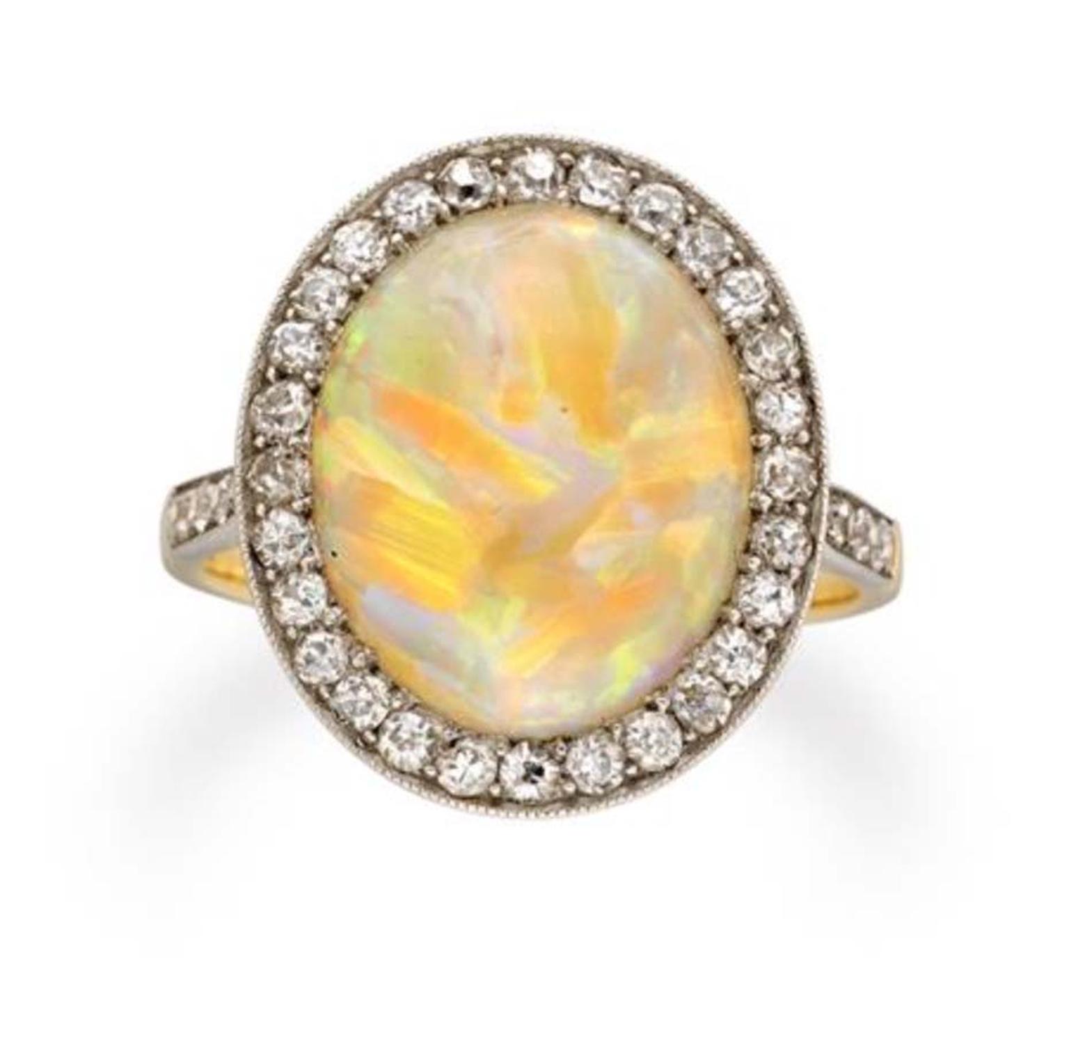 This Edwardian opal and diamond cluster ring circa 1910, available at Bentley & Skinner, has an oval cabochon opal set in the centre of an eight-cut, diamond-set surround, millegrain-set, with diamond-set shoulders.