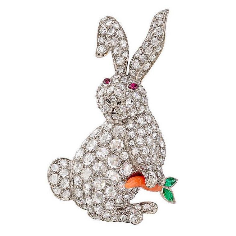 1stdibs white gold rabbit antique jewellery brooch featuring circular-cut diamonds, ruby eyes, and a carved coral carrot with emerald leaves, dates back to the 20th century.