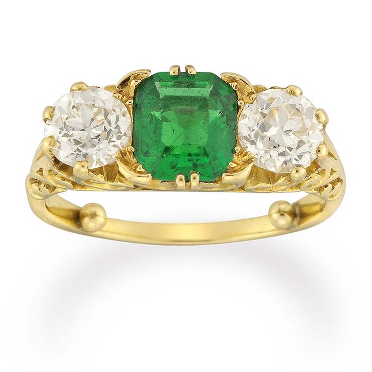 An emerald sits in the centre of this three stone Victorian engagement ring from Bentley & Skinner, flanked by two old-cut diamonds in a carved yellow gold mount.