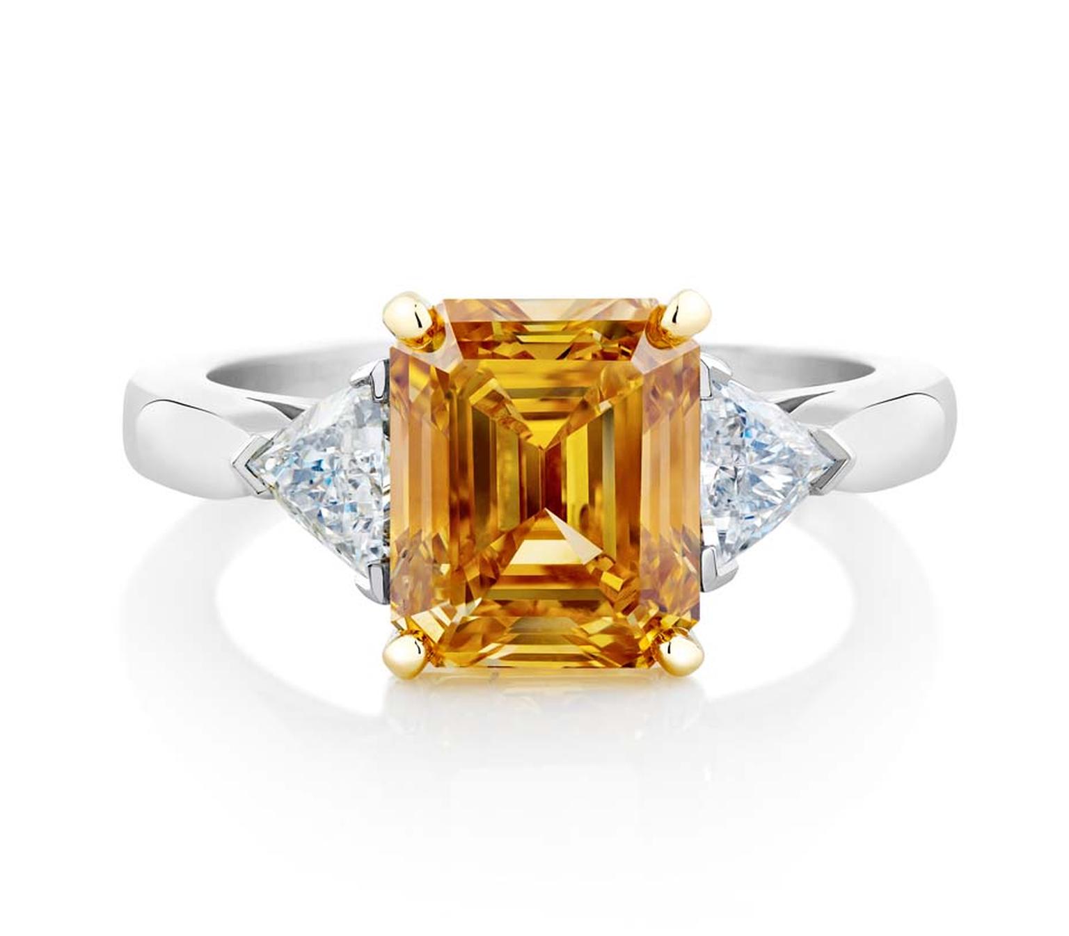 De Beers simple shank emerald-cut Fancy Vivid yellow orange diamond engagement ring in platinum.