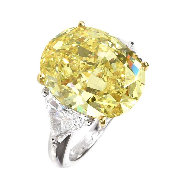 Moussaieff oval cut 14.23ct Natural Fancy Intense Yellow diamond flanked by 1.84ct trillion diamonds and mounted in platinum.
