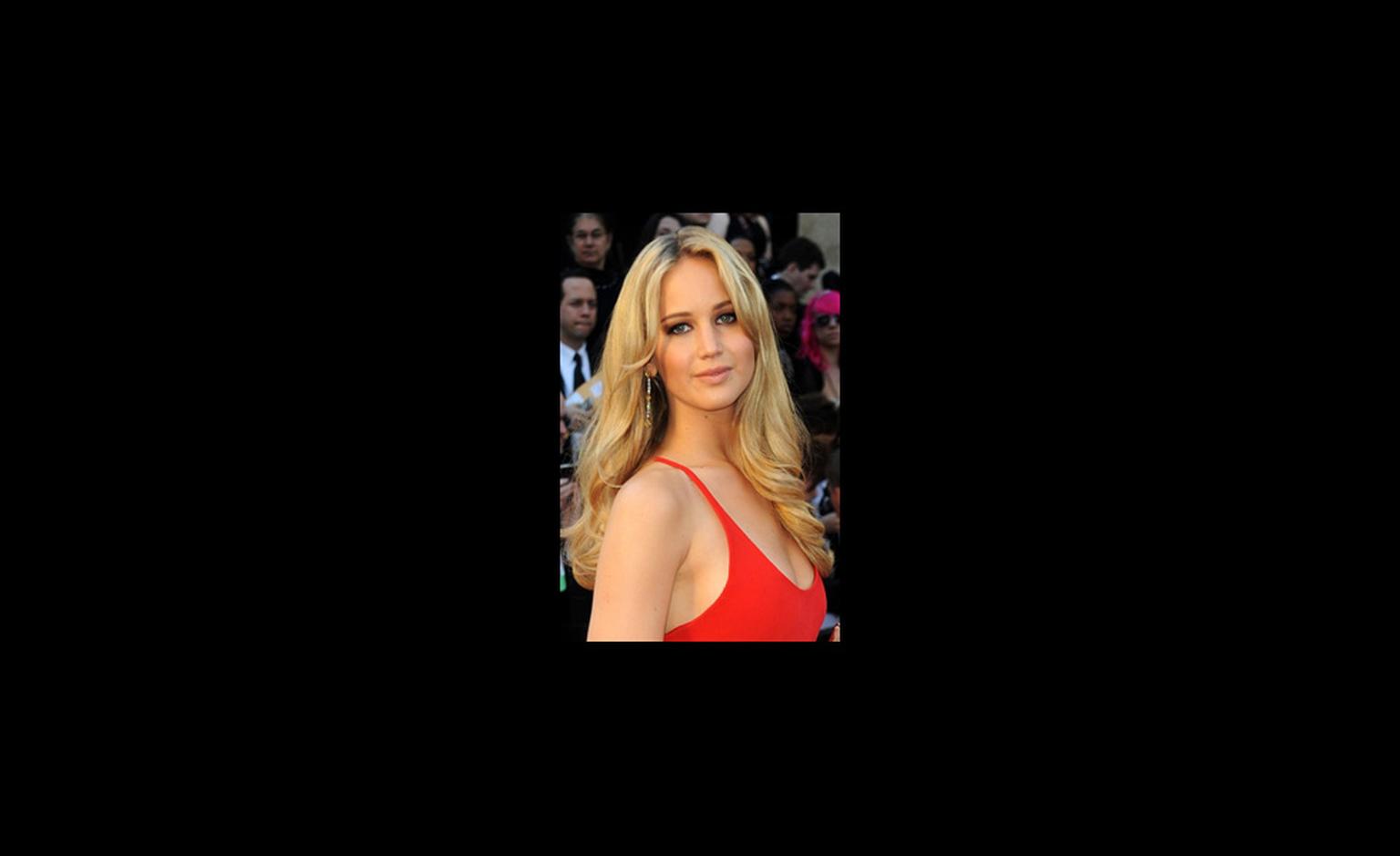 Jennifer Lawrence wears long platinum earrings set with 16 carats of diamonds with a 42 carat diamond bracelet both by Chopard. The diamonds added a flash of light to her pared down look of a red dress by Calvin Klein and long loose hair.